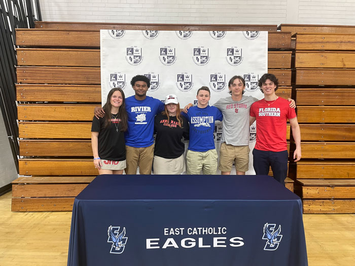 six student athletes at a college signing table