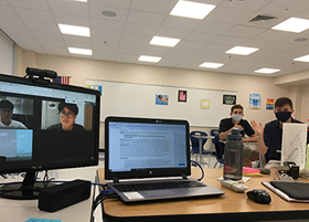 Three people doing a cultural presentation in a classroom